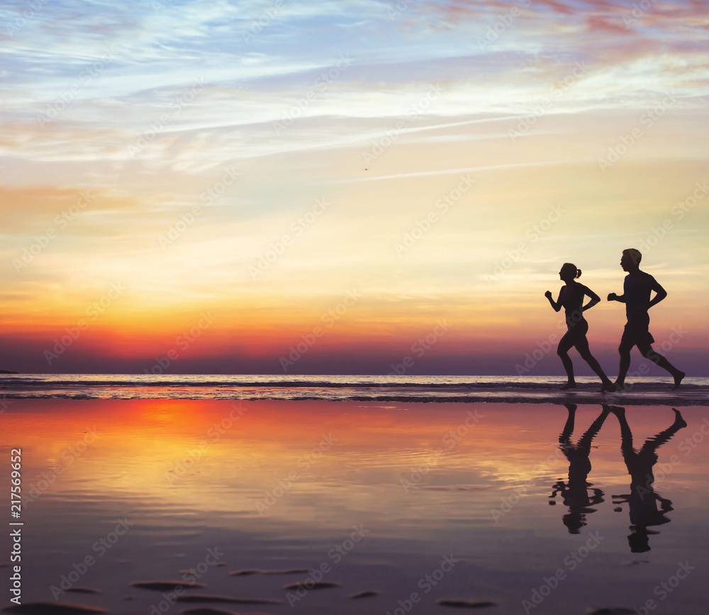 sport and health, two runners on the beach, silhouette of people jogging at sunset, man and woman healthy lifestyle