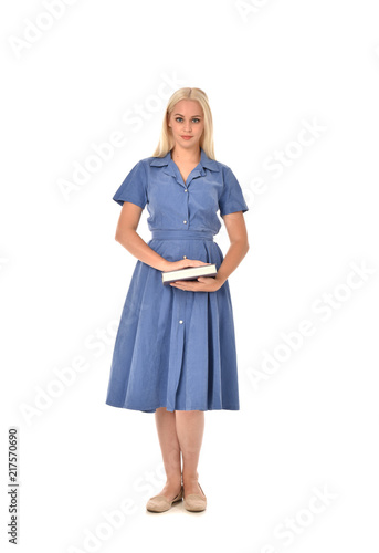 full length portrait of blonde girl wearing blue dress. standing pose holding a book. isolated on white  studio background.