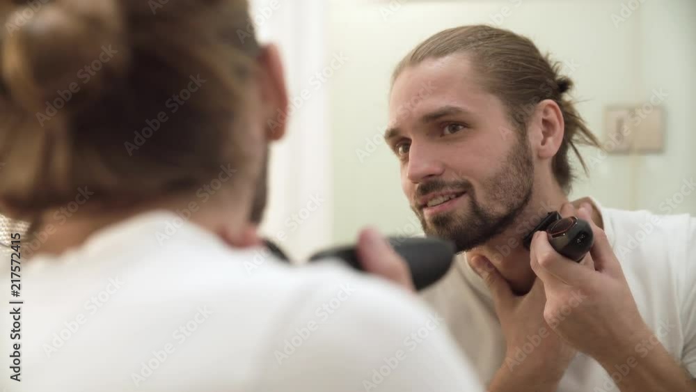 Man Shaving Face With Trimmer Looking In Mirror Man Shaving Face With Trimmer Looking In Mirror