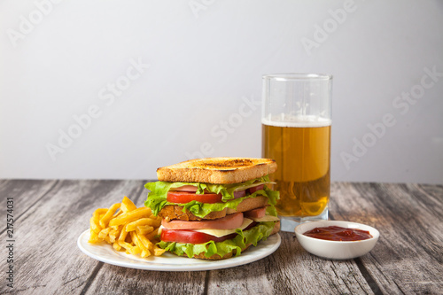 sandwich and fried potatoes on a plate with sauce and beer stand