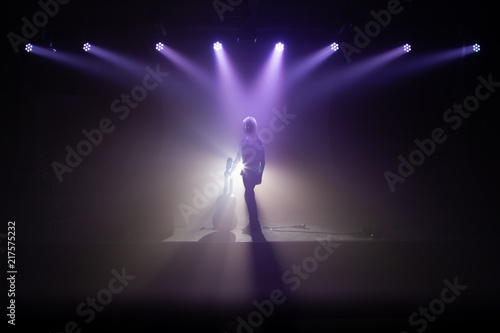 Silhouette eines Mädchens mit Gitarre auf einer Bühne im Rampenlicht mit Nebel © Günter Reuter