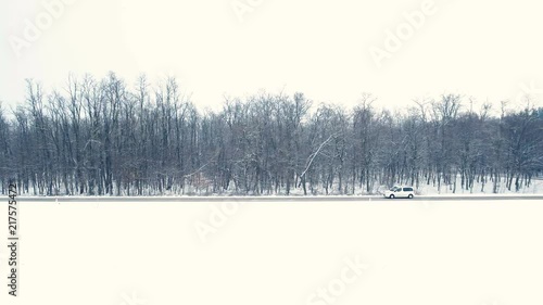 Wallpaper Mural Car travel in winter snow aerial shot 4K. Wide shot of snow landscape with a car vehicle in focus driving on the road with forest in the background. Tracking the vehicle. Torontodigital.ca