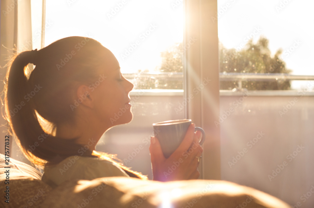 Girl enjoying morning coffee in living room - obrazy, fototapety, plakaty 