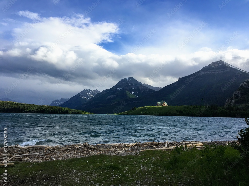 the shoreline of waterton lake on a windy summer's day with the Prince of Wales Hotel sitting on the point