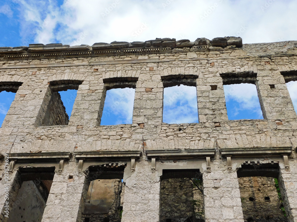 A view of the blue sky through the windows of a historic, residential, ruined building