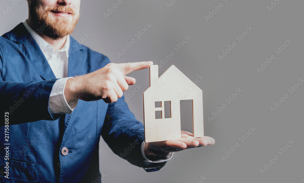 Man proposing signing a estate insurance policy, the agent is holding the wooden house model. Estate insurance concept. Man proposing signing a estate insurance policy, the agent is holding the wooden house model. Estate insurance concept.