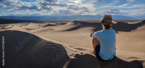 Woman in hat looking out over the Mesquite Flat Sand Dunes in Death Valley National Park at sunset photo