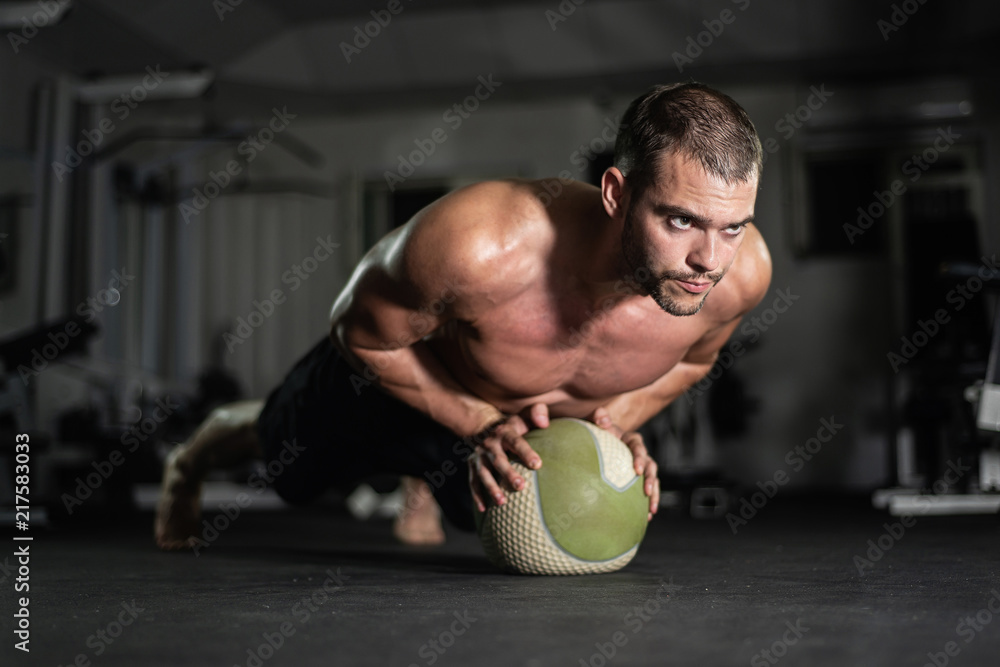 Naklejka premium Fitness man does push-ups on the ball