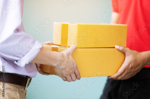 parcel delivery man of a package through a service. and close up hand customer accepting a delivery of boxes from delivery man postal send direct to home. 