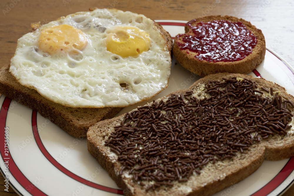 a breakfast with well done eggs, chocolate milk sprinkles and raspberry jam on brown slices of bread on a plate a breakfast with well done eggs, chocolate milk sprinkles and raspberry jam on brown slices of bread on a plate