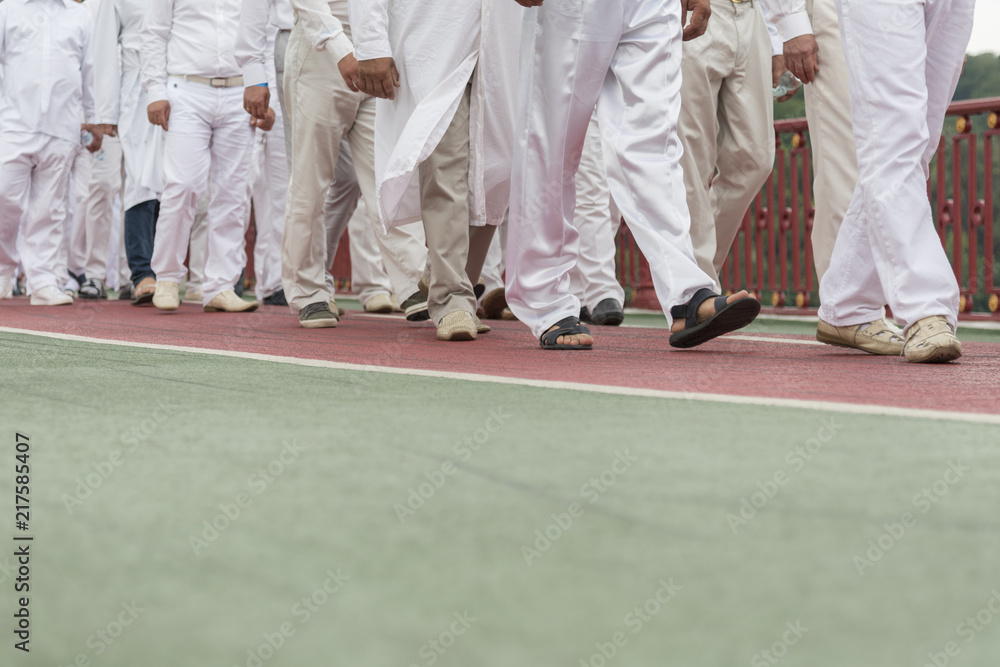 a group of people in white clothes. men in white stags are walking down the street.