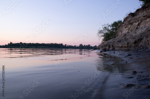 The river bank in the sunset is silent water and yellow sand