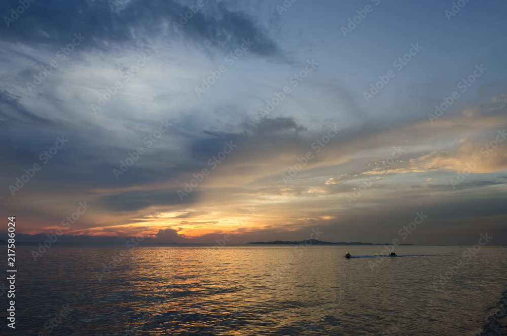 speed boat and banana boat into the sea with sunset