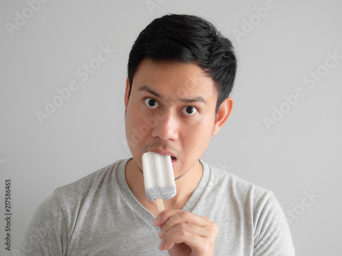 Man eats ice pop with funny face.