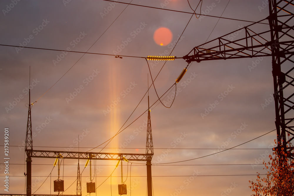 poles at a power plant at sunset as a background