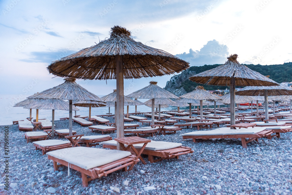 wooden deck chairs and umbrellas on the beach at the sea