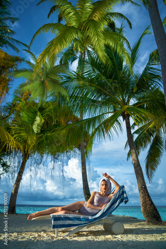 Girl sunbathing on the beach among the palms