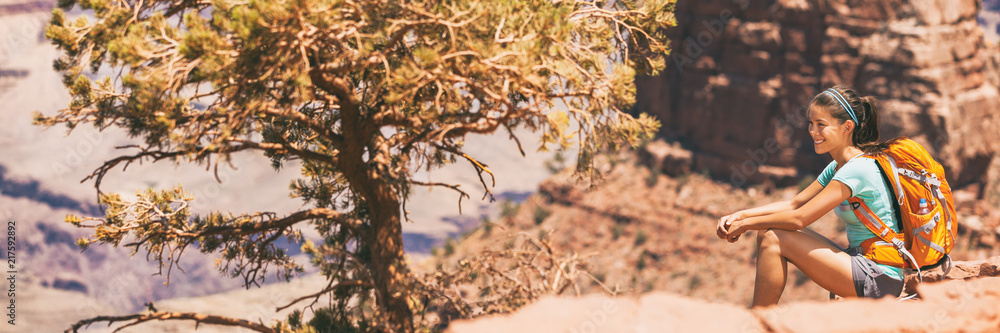 Fototapeta premium Hiker girl hiking on desert hike trail banner panoramic crop of landscape for copy space. Asian woman resting looking at view of nature with backpack.