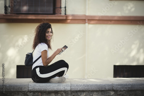 beautiful young woman with backpak using her tablet in the street photo