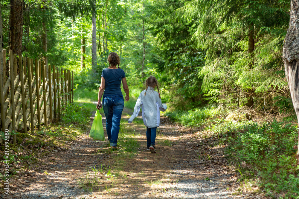 Fototapeta premium Mor och dotter promenerar på en väg genom skogen