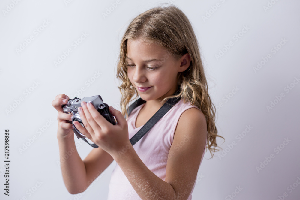 portrait of a young beautiful kid holding a vintage camera and smiling. white background. Kids indoors. Photography concept portrait of a young beautiful kid holding a vintage camera and smiling. white background. Kids indoors. Photography concept