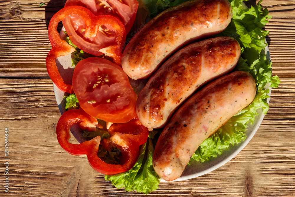 Grilled sausages with fresh vegetables on wooden table Grilled sausages with fresh vegetables on wooden table