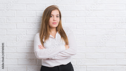Young adult business woman over white brick wall with a confident expression on smart face thinking serious