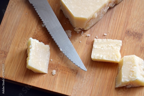 piece of italian grana cheese on wooden chopping board