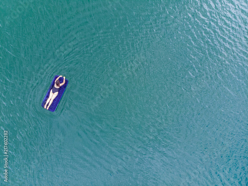 woman on mattress in azure water. overhead view. copy space