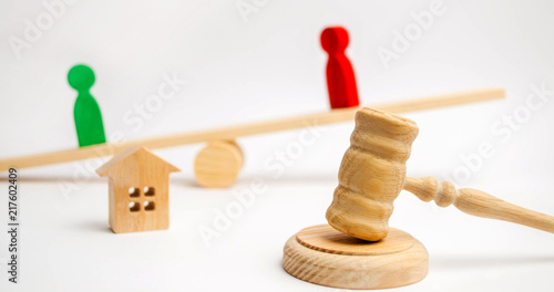 clarification of ownership of the house. wooden figures of people. rivals in business stand on the scales. competition, trial, conflict. victory and defeat. concept of success and power