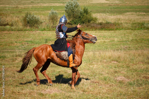 Summer. Reconstruction. Medieval armored knight on horse. Equestrian soldier in historical costume. Reenactor © valyalkin