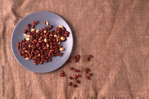 Peanut snacks nuts eating snacks red peanuts peanuts fried peanuts on blue plate on sackcloth. selective focus photo