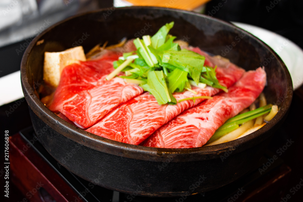Tasty and delicious Japanese Sukiyaki nabe with best-quality cuts of thinly sliced sirloin or rib eye or tenderloin Kuroge Wagyu beef in a cast iron pan. Top and highest Marble Score. Natural light.