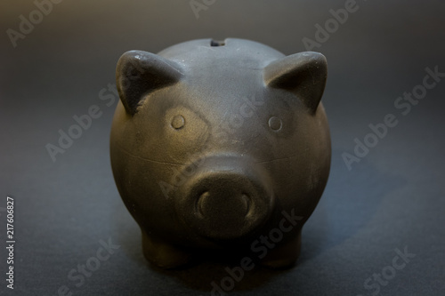 Front of the black piggy bank on the black background, the symbol of saving for a rainy day 