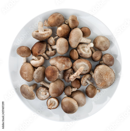 Shiitake mushrooms on a round white plate. Isolated on white background.