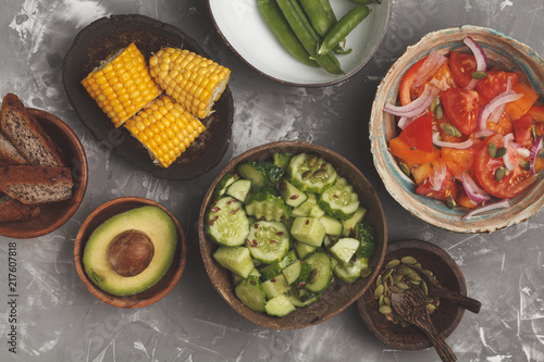 Clean eating concept. Cucumber salad, tomato salad, flax bread, avocado, corn. Top view, food background.