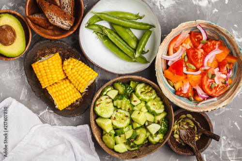 Clean eating concept. Cucumber salad, tomato salad, flax bread, avocado, corn. Top view, food background.