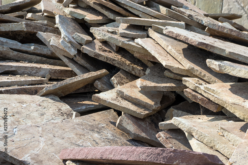 Stone sandstone (slate) is chopped on construction work. A stone of sandstone lies on a pile for building a house.