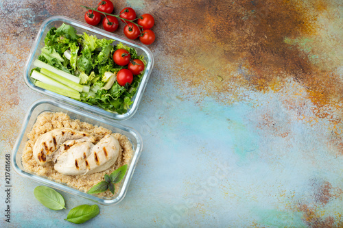 Healthy meal prep containers with quinoa, chicken breast and green salad overhead shot with copy space. Top view. Flat lay