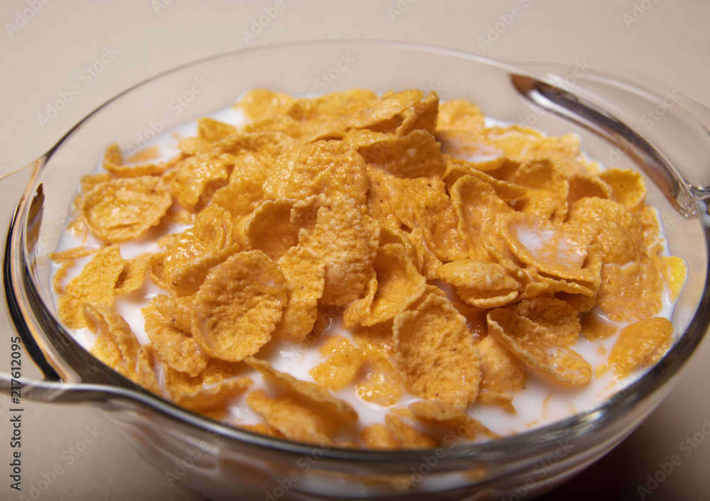 corn flakes in a glass plate with milk on a gray background corn flakes in a glass plate with milk on a gray background