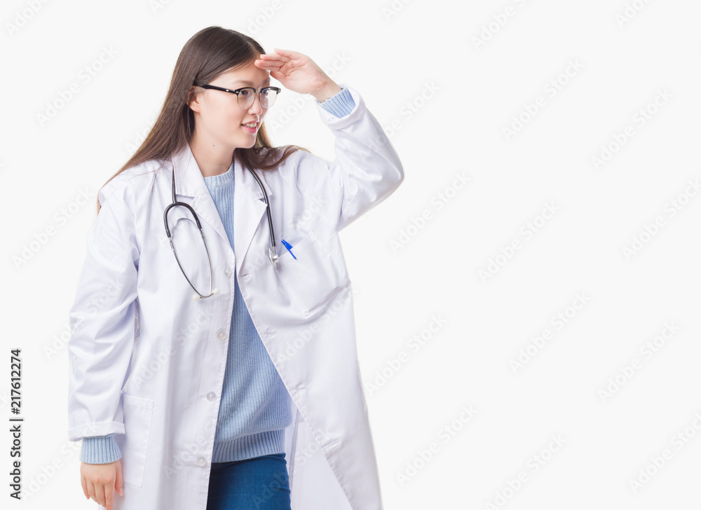 Young Chinese doctor woman over isolated background very happy and smiling looking far away with hand over head. Searching concept. Young Chinese doctor woman over isolated background very happy and smiling looking far away with hand over head. Searching concept.
