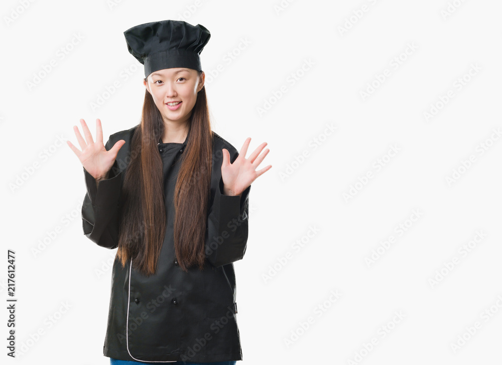 Young Chinese woman over isolated background wearing chef uniform showing and pointing up with fingers number ten while smiling confident and happy. Young Chinese woman over isolated background wearing chef uniform showing and pointing up with fingers number ten while smiling confident and happy.