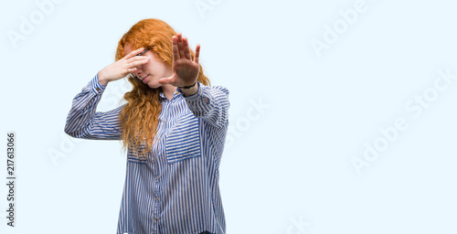 Young redhead bussines woman covering eyes with hands and doing stop gesture with sad and fear expression. Embarrassed and negative concept.