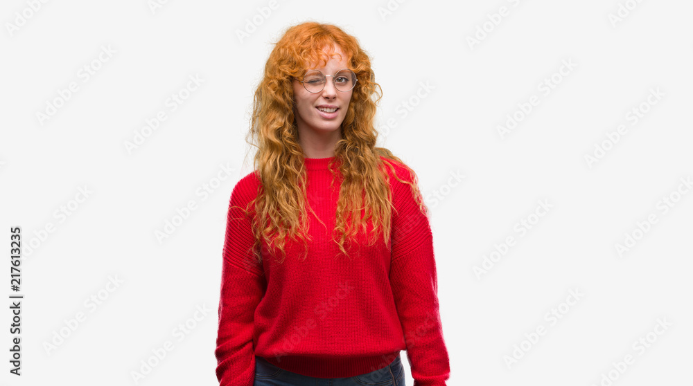 Young redhead woman wearing red sweater winking looking at the camera with sexy expression, cheerful and happy face. Young redhead woman wearing red sweater winking looking at the camera with sexy expression, cheerful and happy face.