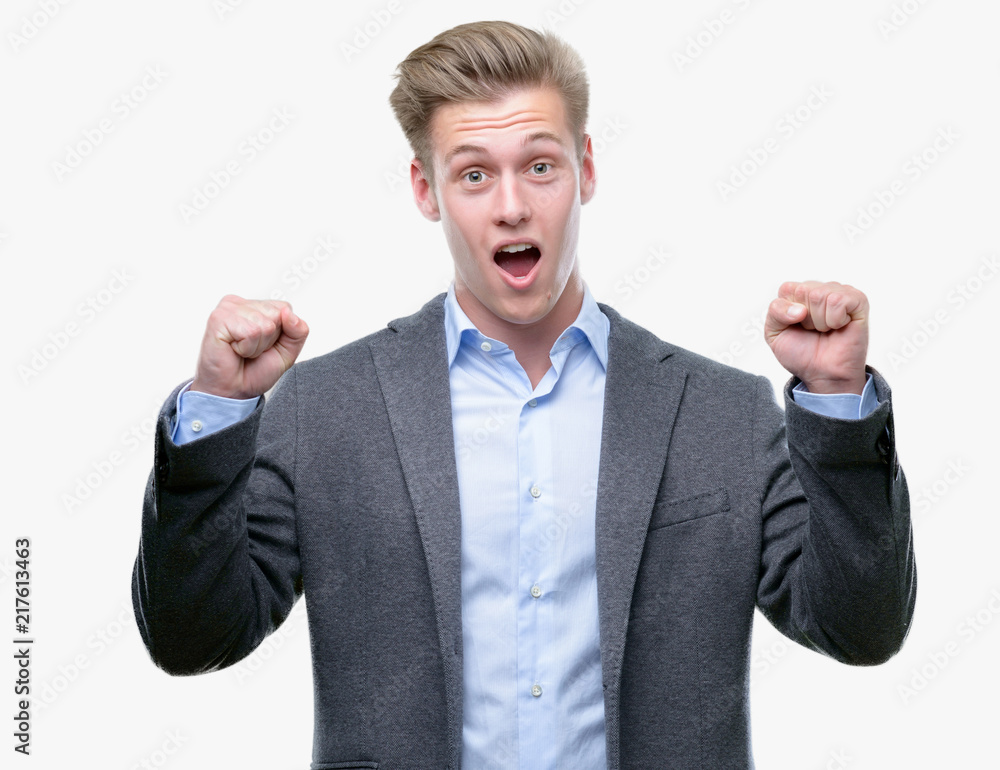 Young handsome blond business man celebrating surprised and amazed for success with arms raised and open eyes. Winner concept. Young handsome blond business man celebrating surprised and amazed for success with arms raised and open eyes. Winner concept.