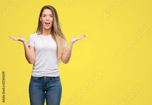 Beautiful young woman wearing t-shirt and jeans very happy and excited, winner expression celebrating victory screaming with big smile and raised hands