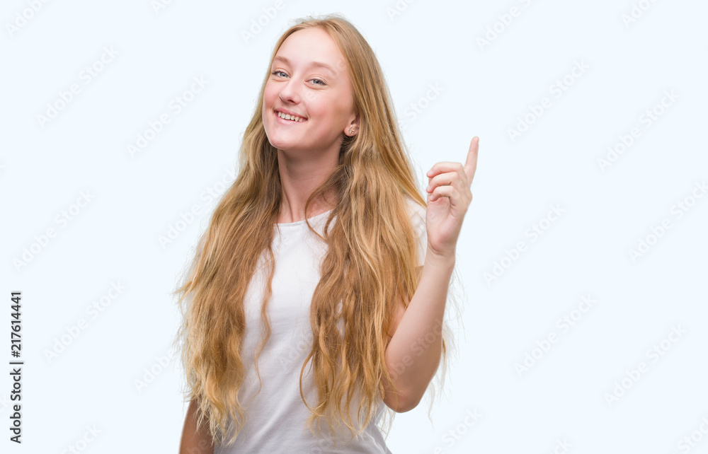 Blonde teenager woman surprised with an idea or question pointing finger with happy face, number one Blonde teenager woman surprised with an idea or question pointing finger with happy face, number one