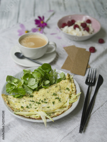 Omelet with zucchini and mushrooms. Cozy breakfast: omelette with zucchini,  cottage cheese with raspberries, bread and a cup of coffee. Healthy food. Close up, copy space