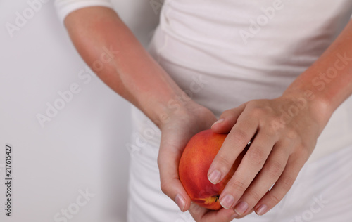 Woman suffering from Fruit Allergy holding a peach. OAS, food allergy symptoms rush, itching, skin redness.