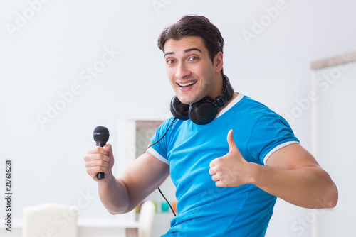 Young handsome man singing karaoke at home 